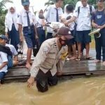 Bhabinkamtibmas Desa Benggaulu Bantu Pelajar Menyeberangi Banjir